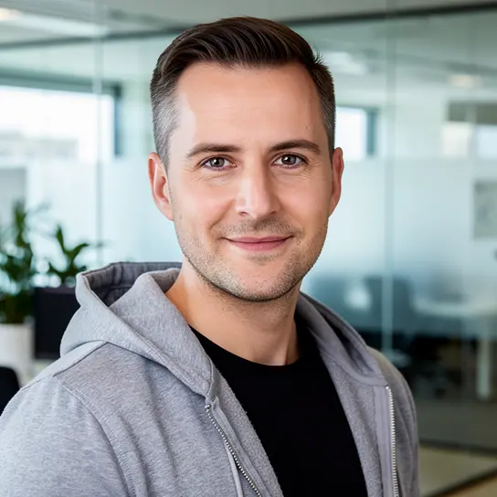 AI generated headshot: Same person in a casual hoodie with a modern open-office background (Startup look)